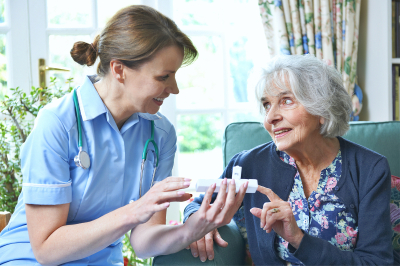 Nurse Advising Senior Woman On Taking Medication At Home