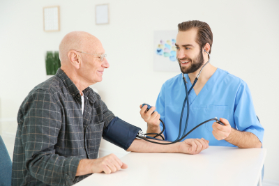 nurse measuring blood pressure of senior man at home